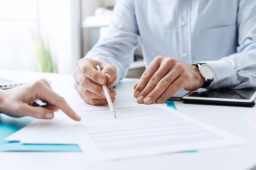 Person hält Stift und zeigt auf Formular