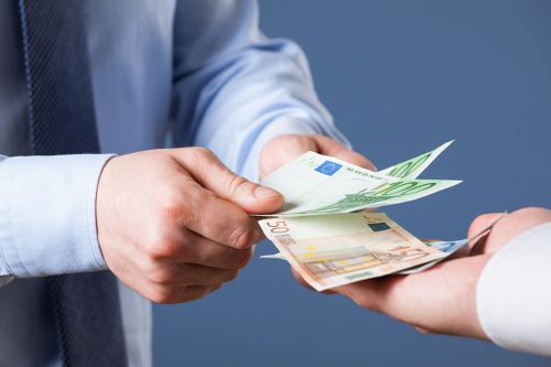 zwei Hände übergeben Geldscheine in eine dritte Hand
