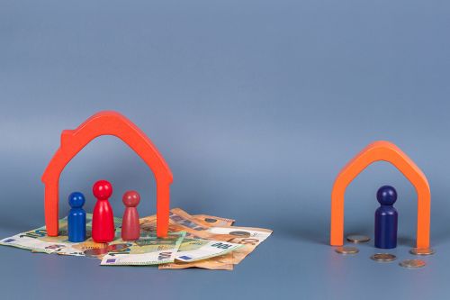 Spielsteine stehen auf Geldscheinen unter einem Haus